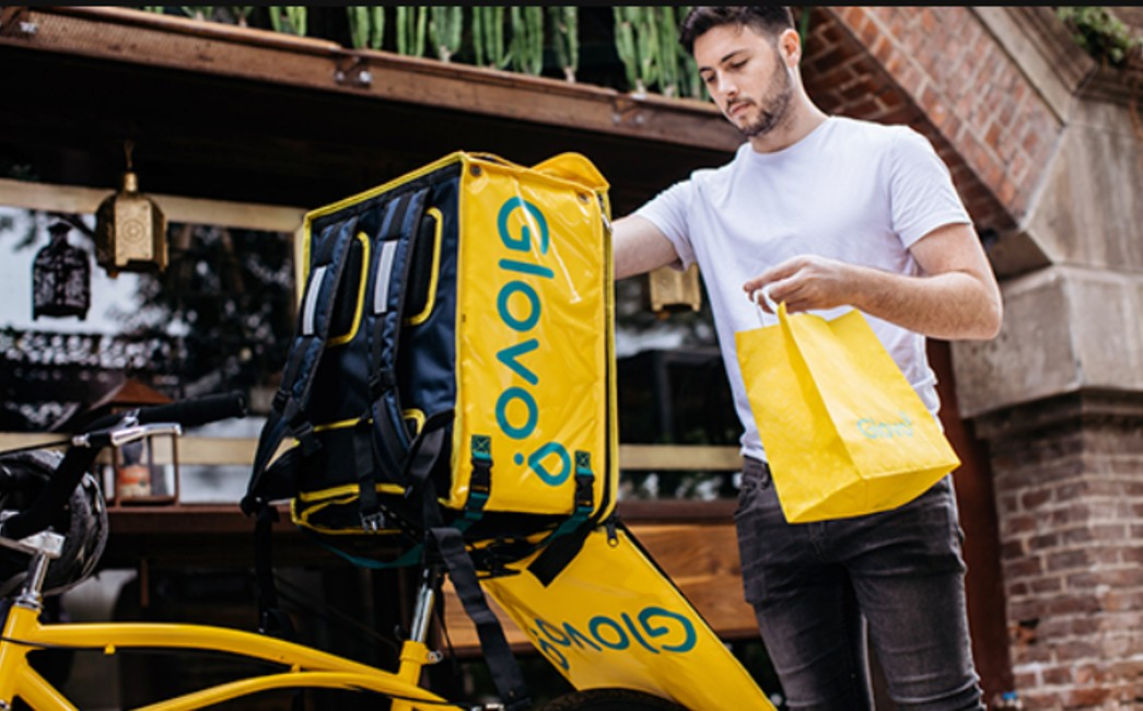 Glovo dostavljač sa žutom Glovo termalnom torbom na biciklu
