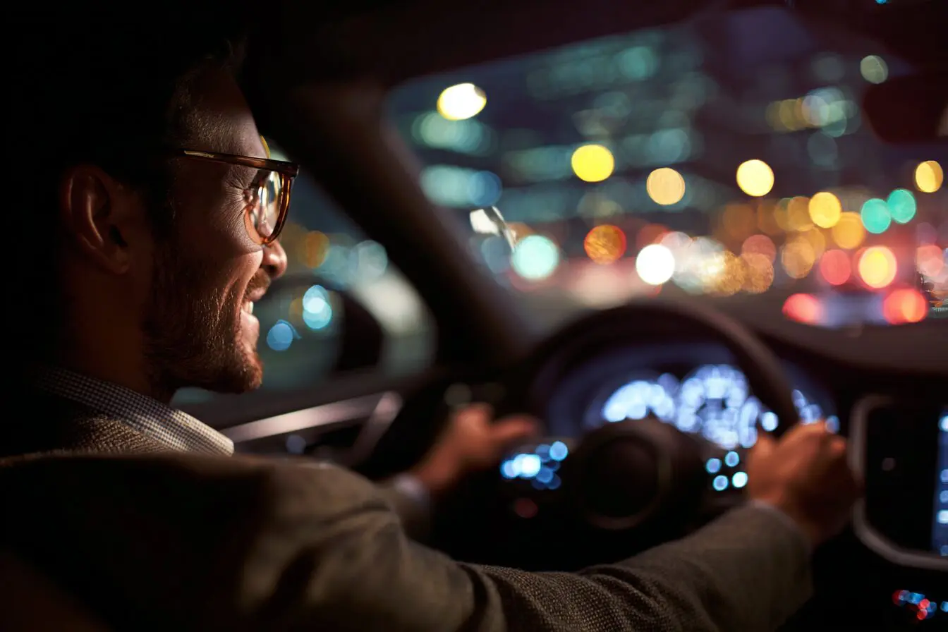 Vozač vozi automobil noću kroz grad — posao vozača za Uber i Bolt